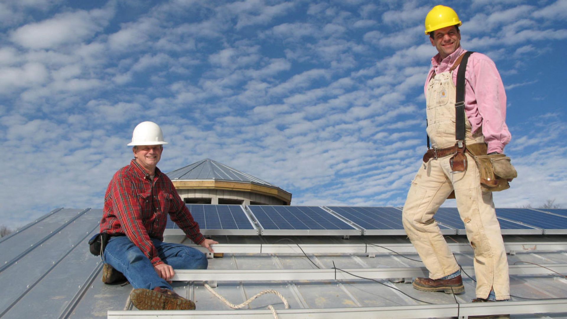 Lightwave founder Steve Johnson and coworker on building roof working on solar panel installation